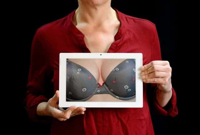 la femme tient une photo de son buste dans un soutien-gorge push up